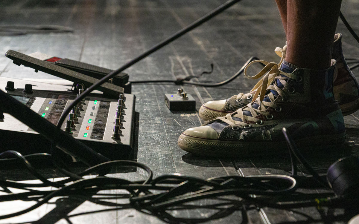 Guitarist with a digital modeller pedalboard on stage